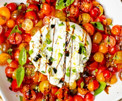 Serving of burrata salad on a white platee.