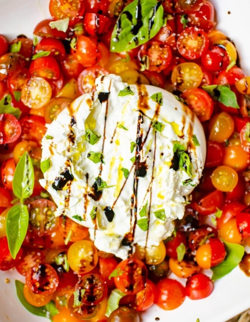 Serving of burrata salad on a white platee.