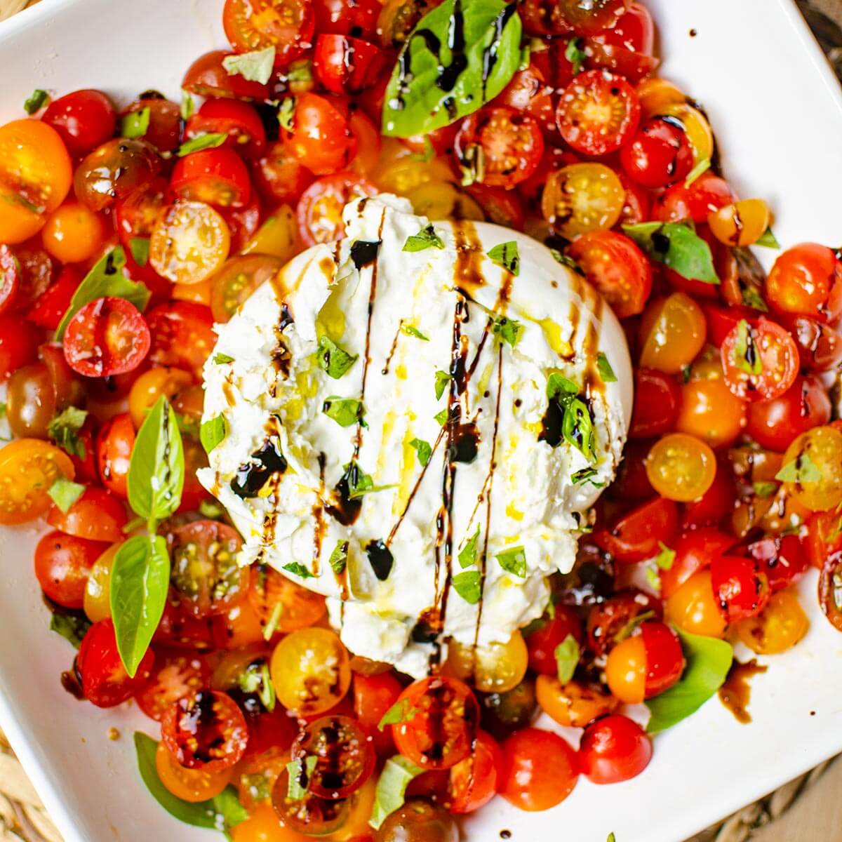 Serving of burrata salad on a white platee.