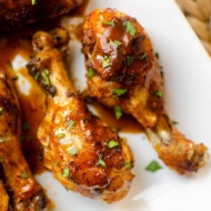 Close up of drumsticks on a plate with gravy and sprinkled with parsley.