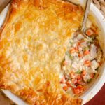 Closeup of pot pie in a pie plate, with a slice taken out.