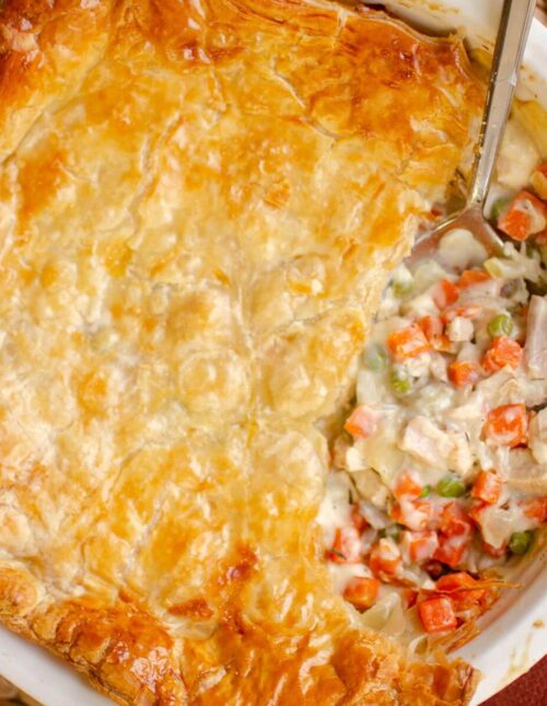 Closeup of pot pie in a pie plate, with a slice taken out.