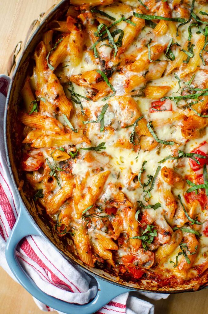 Meatless baked ziti in a blue dish with fresh basil on top.