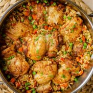 Cooked chicken and rice in a pan with parsley on top.