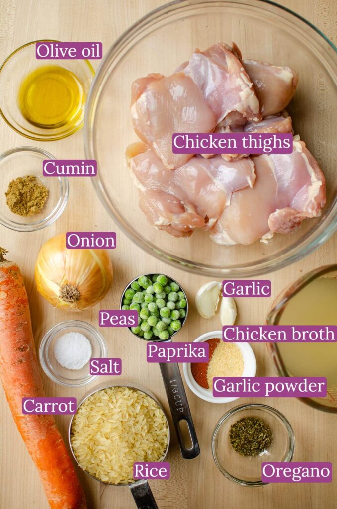 Ingredients for one pot chicken thighs and rice on a wooden board.