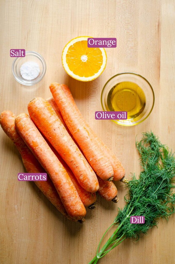 Ingredients for dill carrots on a wooden cutting board.