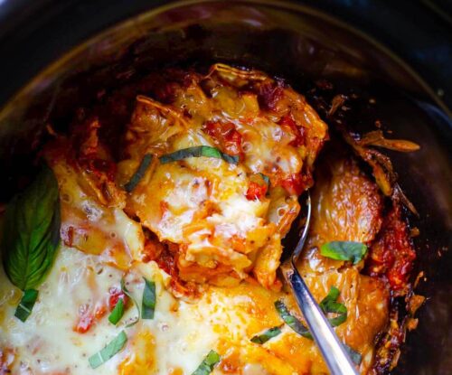 Closeup of a serving of lasagna being taken out of the crockpot.