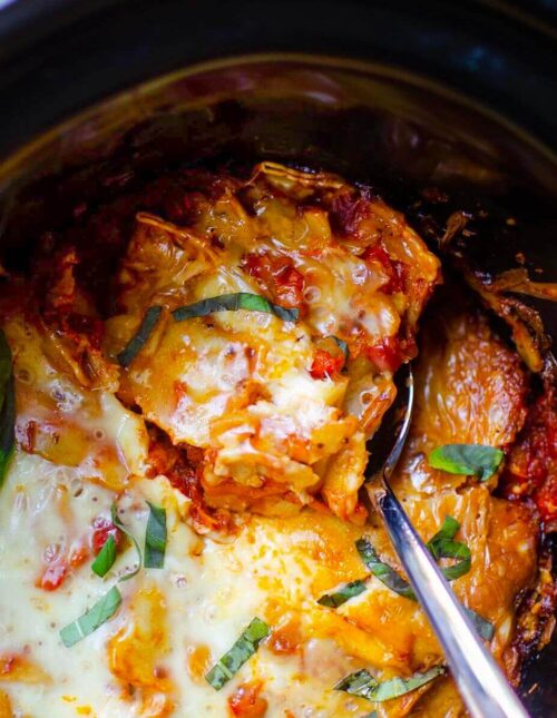 Closeup of a serving of lasagna being taken out of the crockpot.