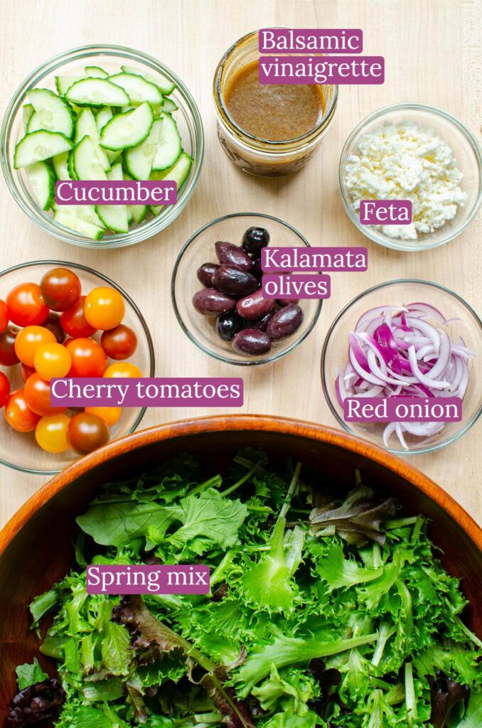 Ingredients for salad on a wooden board in small glass bowls.