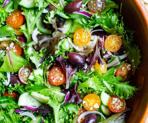 Closeup of green salad with tomatoes, red onions, feta cheese and cucumber.