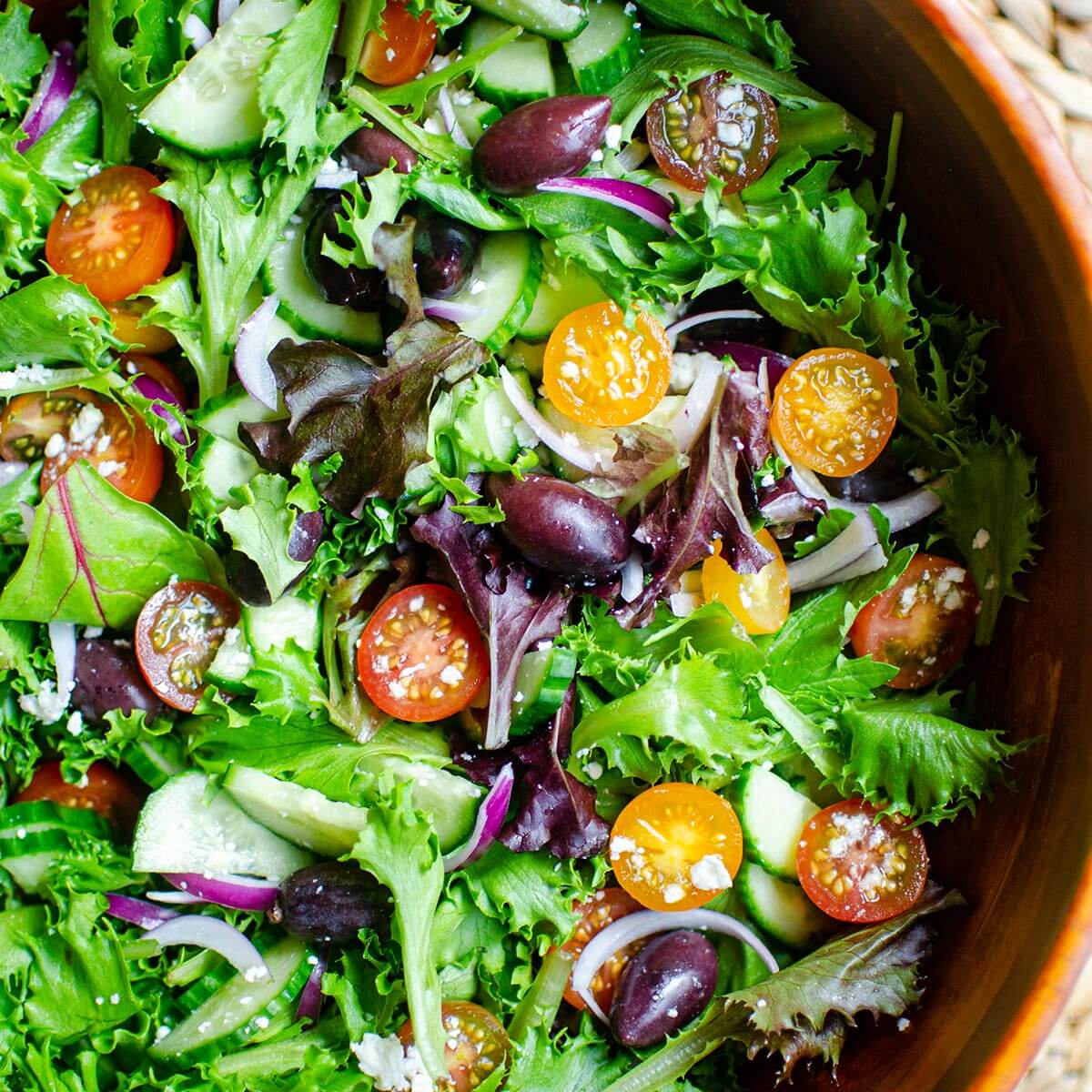 Closeup of green salad with tomatoes, red onions, feta cheese and cucumber.