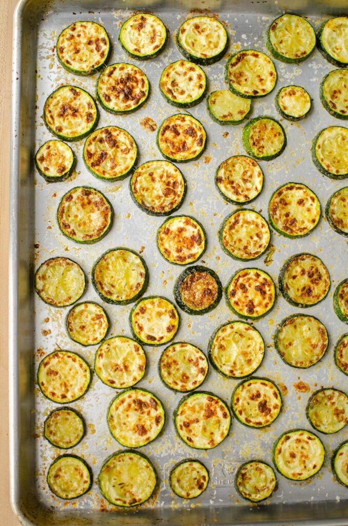 Cooked zucchini slices on a baking sheet.