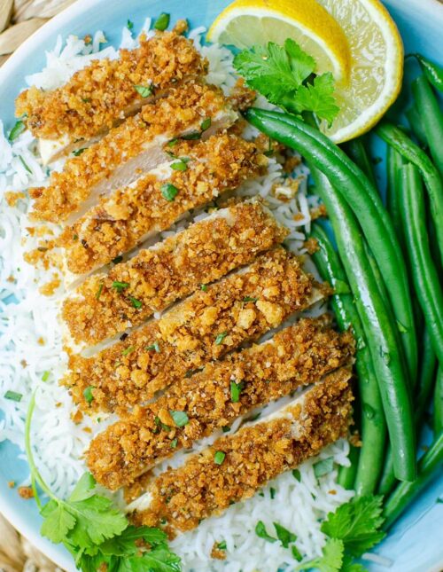 Closeup of a plate of chicken with rice and green beans.