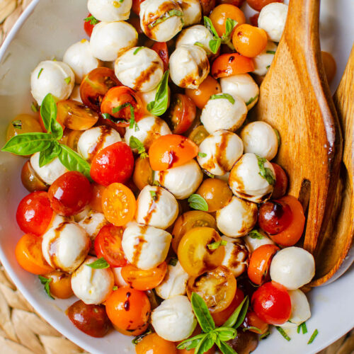 Salad in white salad bowl with wooden salad spoons.