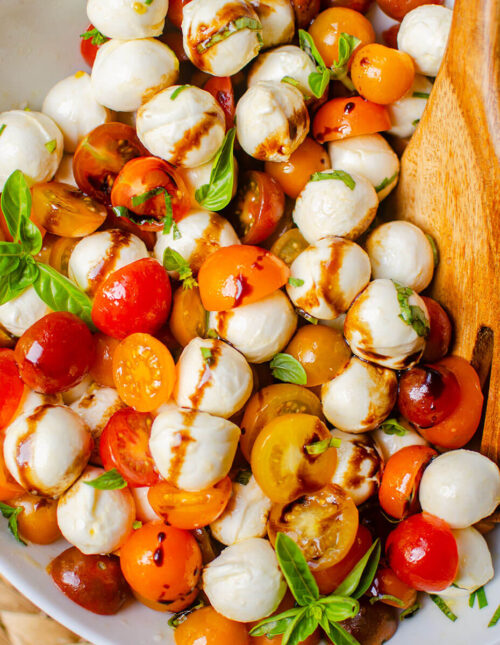 Salad in white salad bowl with wooden salad spoons.