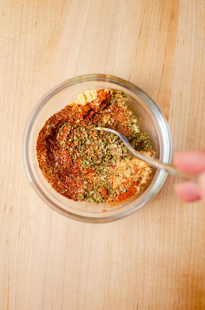 Spice rub ingredients being combined in a glass bowl.