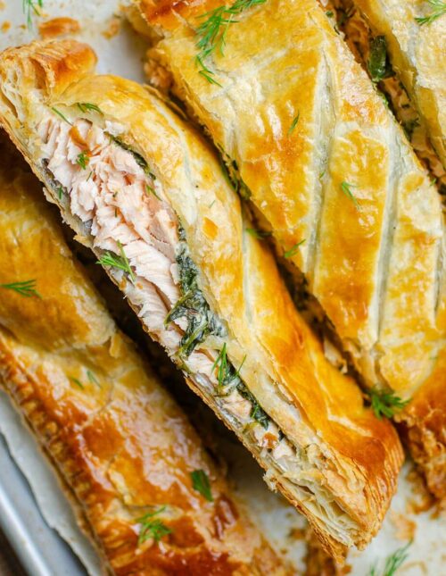 Closeup of four pieces of salmon wellington on a baking sheet.