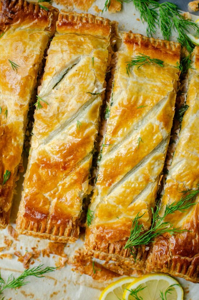 Closeup of four pieces of salmon wellington, with dill sprinkled overtop.