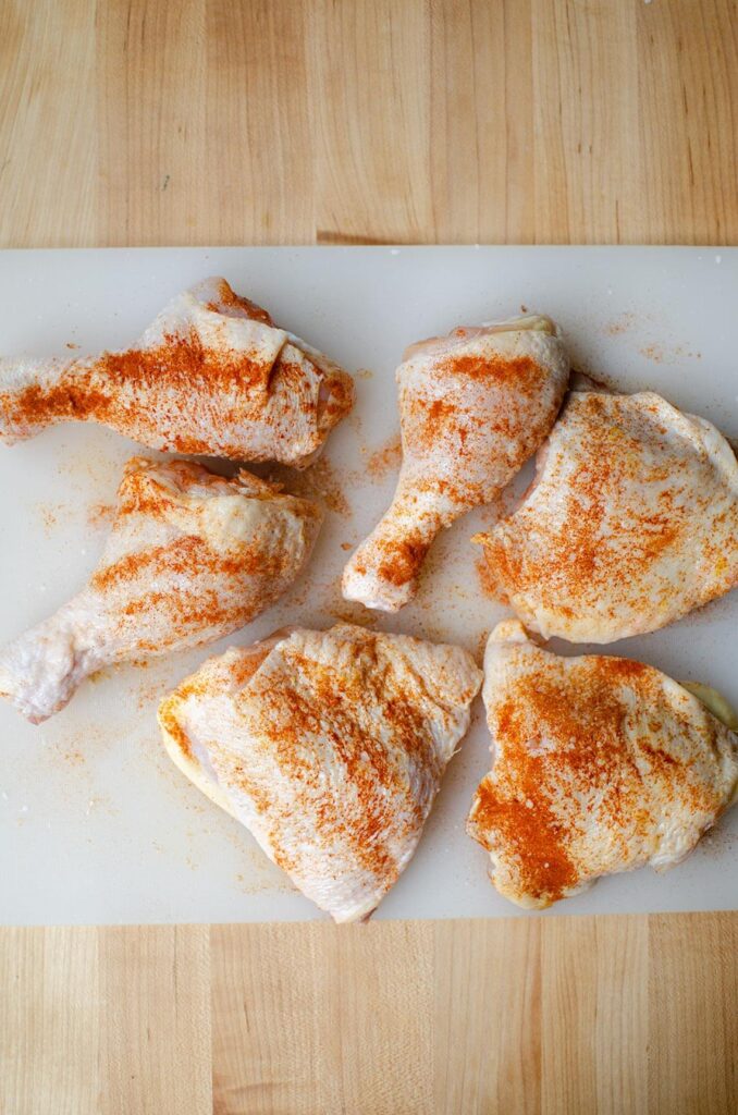 Chicken with paprika sprinkled on top on a cutting board.
