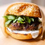 Closeup of burger wrapped in parchment paper.