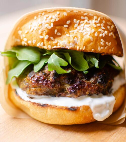 Closeup of burger wrapped in parchment paper.
