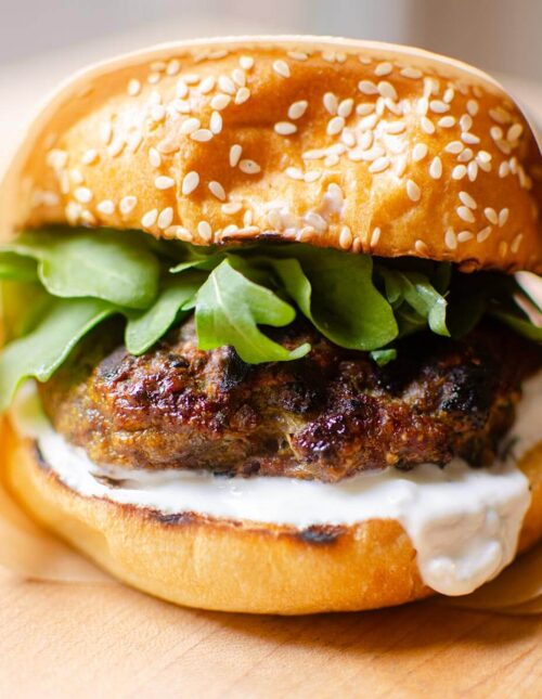 Closeup of burger wrapped in parchment paper.