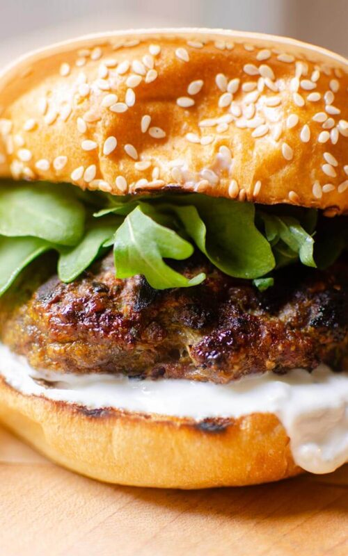 Closeup of burger wrapped in parchment paper.