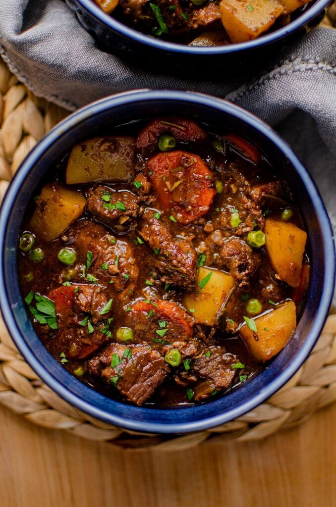 One serving of stew in a blue bowl with parsley sprinkled on top.
