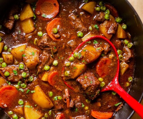 Closeup of a ladle in finished beef stew.
