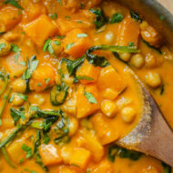 Closeup of butternut squash chickpea curry with a wooden serving spoon.