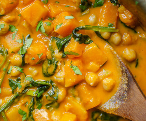 Closeup of butternut squash chickpea curry with a wooden serving spoon.